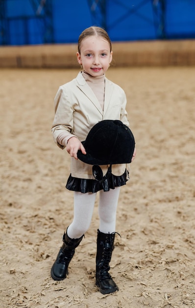 Ragazza carina in fantino che indossa Giovane bambino grazioso con casco da cavallo