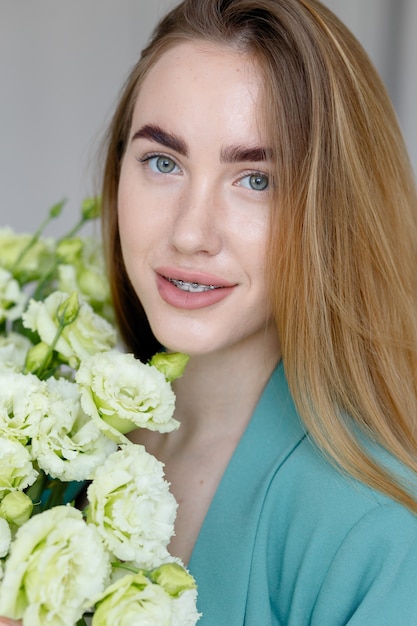 Ragazza carina in giacca verde con in mano un bouquet