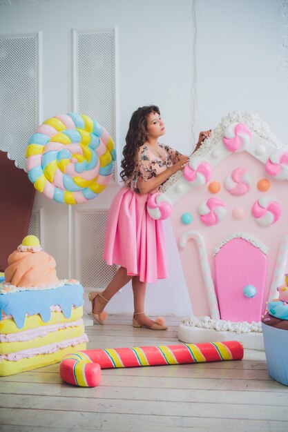 Ragazza carina in posa con ciambelle rosa, scherzare, dessert, cibo cattivo, guarda nel buco nella ciambella, mantiene le ciambelle dagli occhi