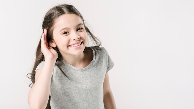 Ragazza carina in studio che mostra il segno dell&#39;udito