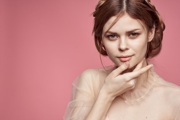 Ragazza carina in un vestito delicato in posa su uno sfondo rosa e sorridente