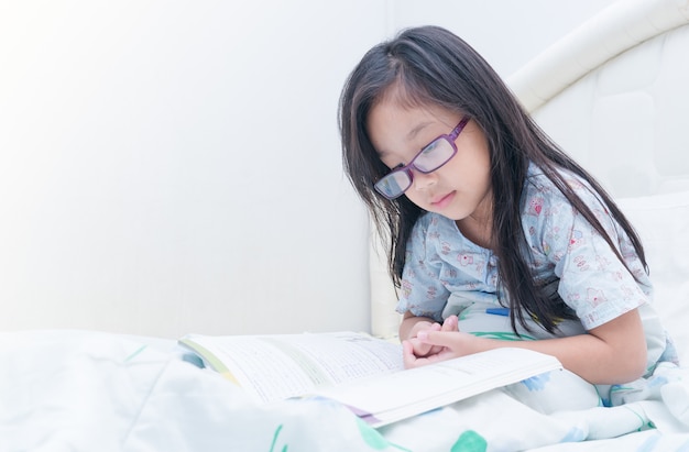 ragazza carina leggendo il libro sul letto