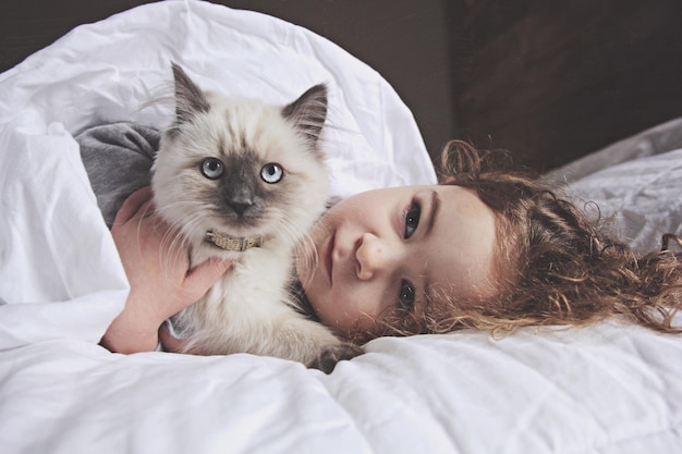 Ragazza carina sdraiata con il gatto sul letto