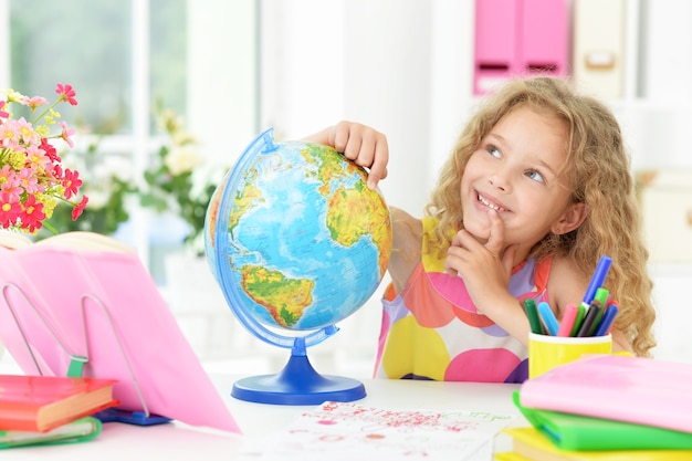 Ragazza carina studentessa con libri e globo in classe