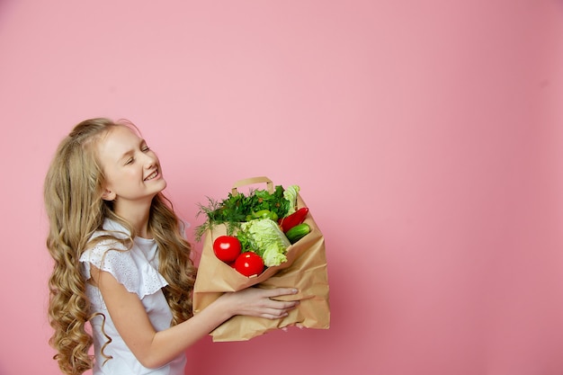 Ragazza carina su uno sfondo rosa con verdure