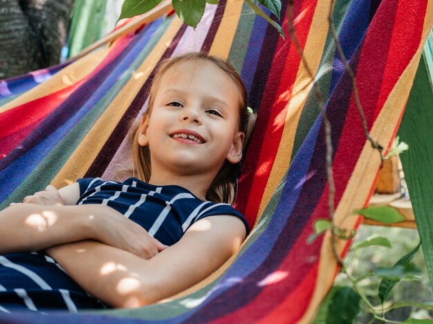 Ragazza carina sullo sfondo estivo dell'amaca colorata, attività all'aperto per le vacanze estive