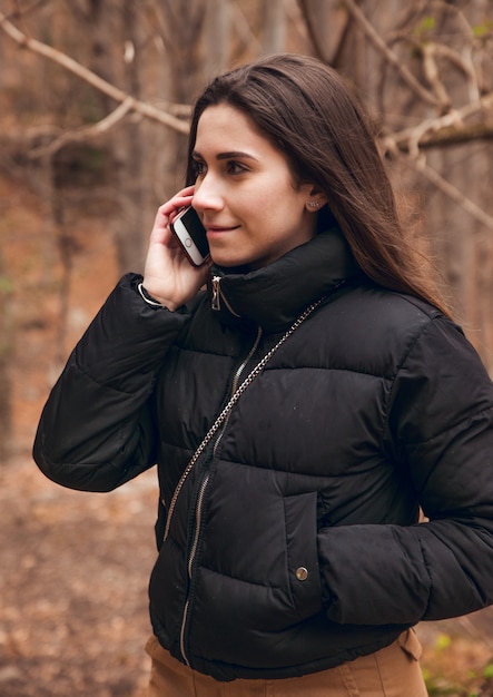 Ragazza castana che chiama dal telefono nella foresta