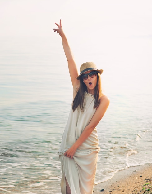 Ragazza casuale allegra che cammina su una spiaggia del mare e grida felici.