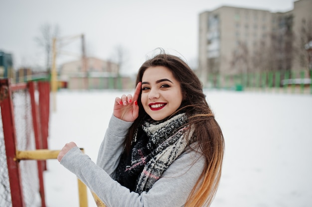 Ragazza casuale castana in sciarpa all'inverno sulla via.