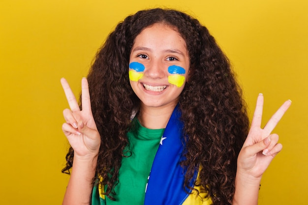 Ragazza caucasica brasiliana tifoso di calcio closeup foto espressione di pace e amore le dita sollevate felice posa per foto Olimpiadi della Coppa del mondo