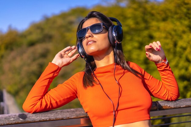 Ragazza caucasica castana che gode della musica con le cuffie in un parco