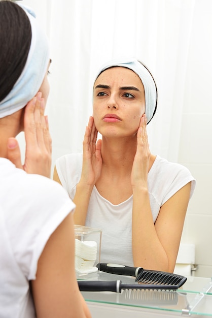 ragazza caucasica che applica la maschera facciale davanti allo specchio