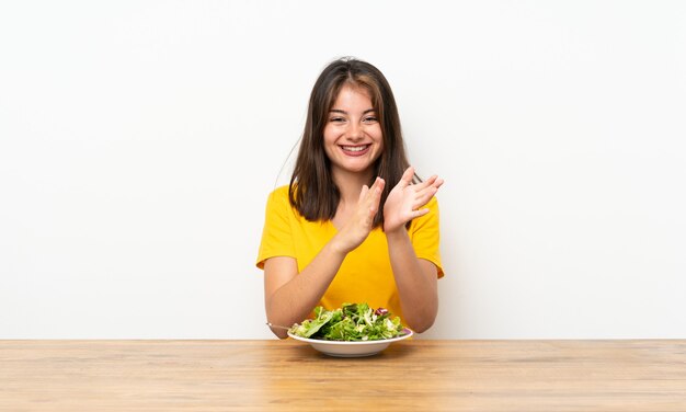 Ragazza caucasica con insalata che applaude