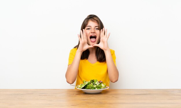 Ragazza caucasica con insalata che grida con la bocca spalancata