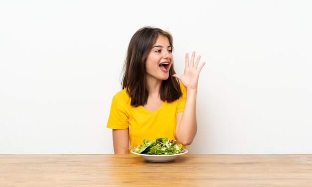 Ragazza caucasica con insalata che grida con la bocca spalancata