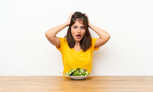 Ragazza caucasica con insalata con espressione facciale a sorpresa