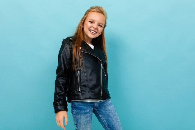 Ragazza caucasica dell'adolescente nei sorrisi neri dei jeans e del rivestimento isolati su fondo blu