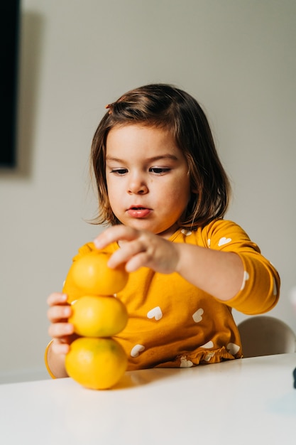 Ragazza caucasica divertendosi con i mandarini. Dieta sana del bambino. Potenziamento immunitario con vitamina c