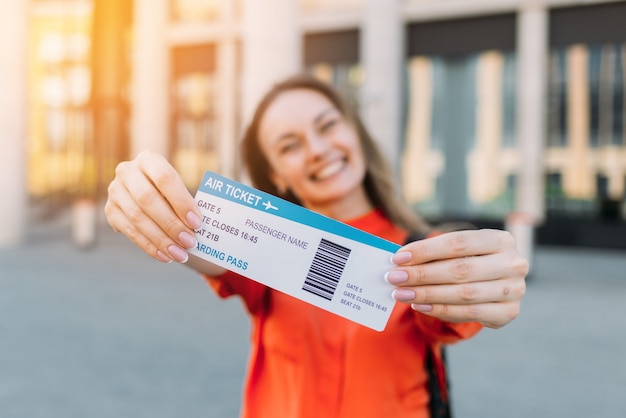 Ragazza caucasica gioiosa in possesso di un biglietto aereo per l'aereo e viaggia nelle sue mani.