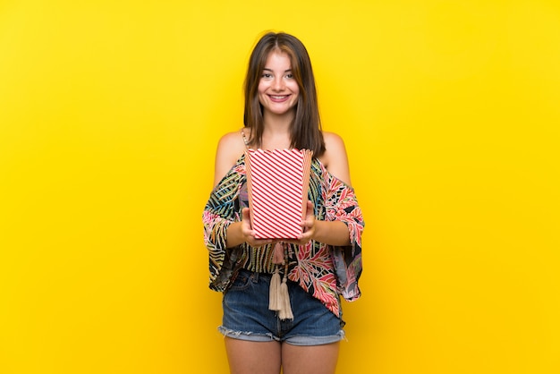 Ragazza caucasica in abito colorato in possesso di una ciotola di popcorn