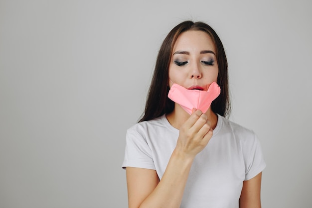 Ragazza caucasica in mezzo a un muro bianco sullo sfondo che indossa una maschera protettiva rosa fatta a mano