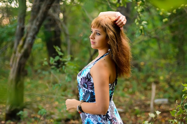 Ragazza caucasica in vestito blu che posa nella foresta di estate