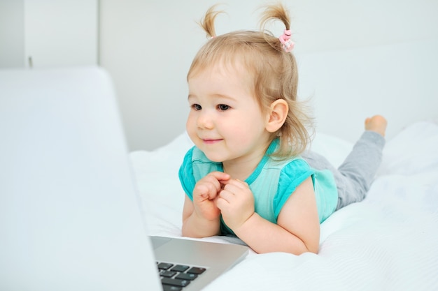 Ragazza caucasica sorridente felice del bambino che gioca sul computer portatile