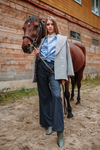 Ragazza cavaliere in piedi accanto al cavallo