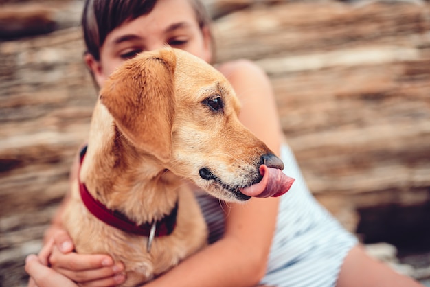 Ragazza che abbraccia cane mentre lecca il naso