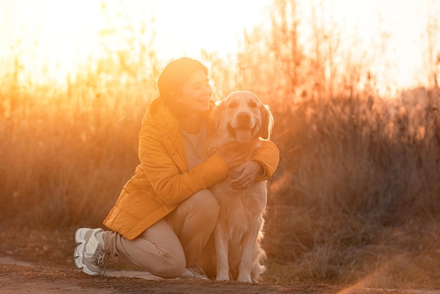 Ragazza che abbraccia il cane del documentalista dorato con la luce del tramonto all'aperto. Giovane donna che accarezza doggy pet labrador in natura in autunno