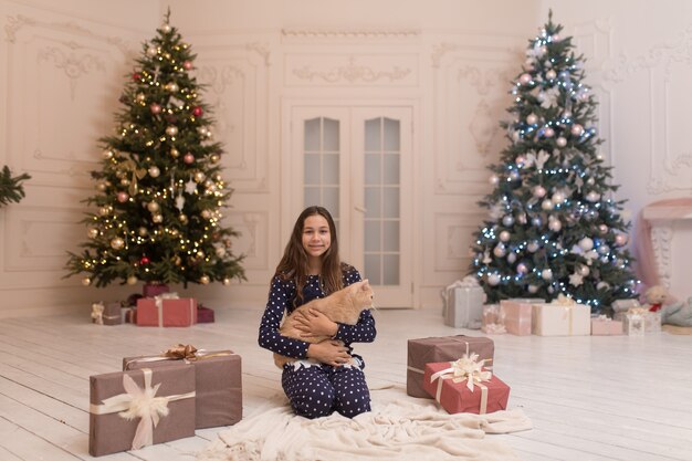 Ragazza che abbraccia il gatto che ha ricevuto come regalo per Natale