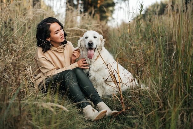 ragazza che abbraccia un cane golden retriever nel campo