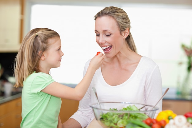 Ragazza che alimenta sua madre con pomodoro