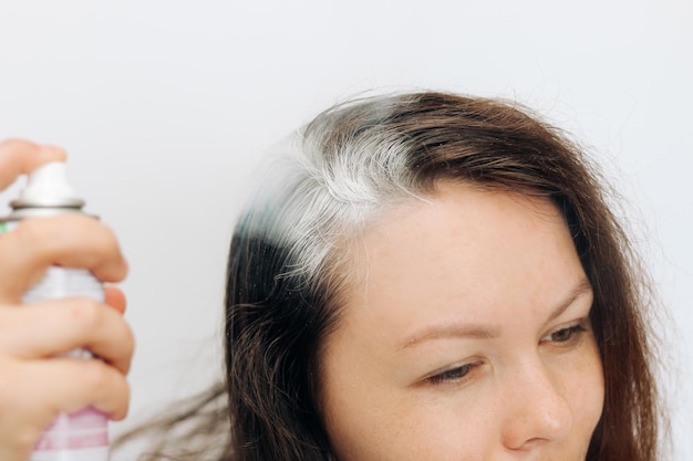 Ragazza che applica uno shampoo secco spray sulle radici di capelli scuri e soffici