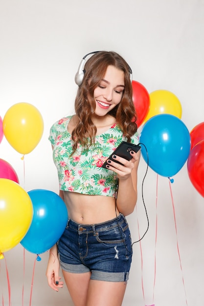 Ragazza che ascolta la musica con le cuffie accanto ai palloncini