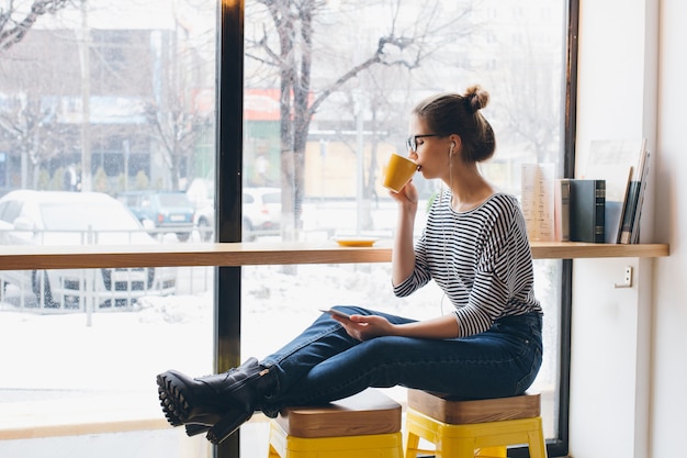 Ragazza che ascolta la musica sul tuo smartphone e che beve caffè