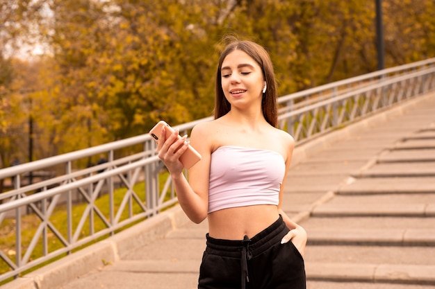 Ragazza che ascolta la musica sulle cuffie e cerca qualcosa nel suo telefono cellulare