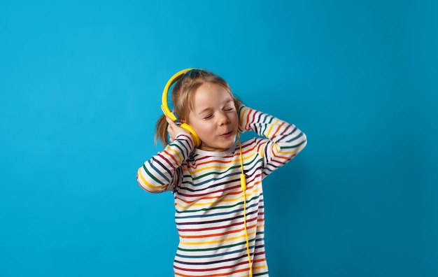 ragazza che ascolta la sua canzone preferita con le cuffie gialle su sfondo blu