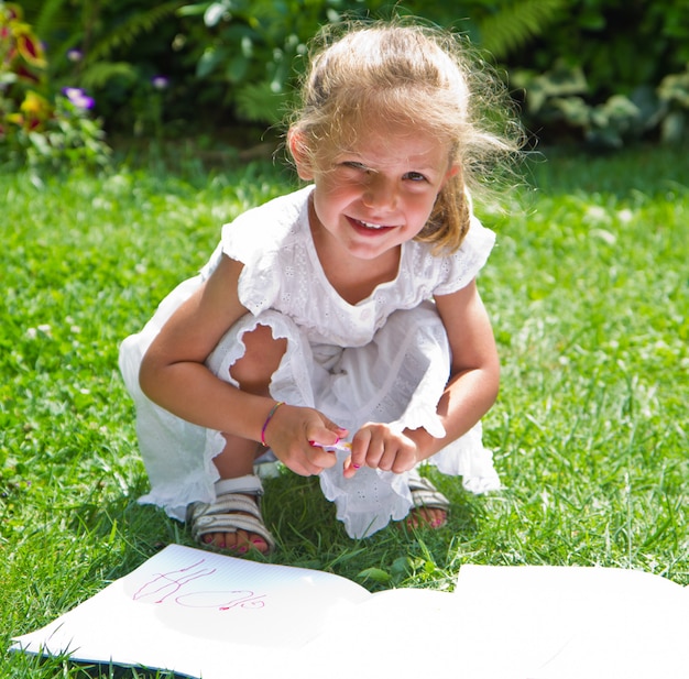 Ragazza che attinge libro sull'erba