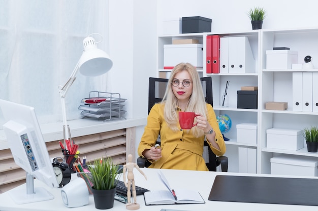 Ragazza che beve caffè che lavora al computer