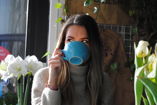 Ragazza che beve caffè in una tazza blu a casa