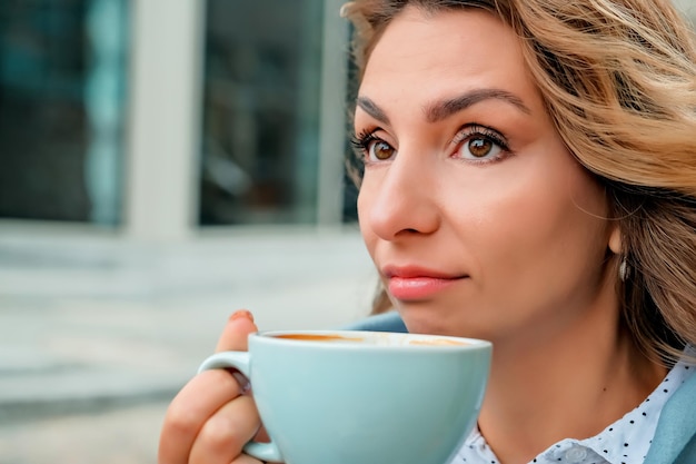 Ragazza che beve caffè per strada una tazza di caffè una tazza di caffè e il primo piano del viso di una ragazza