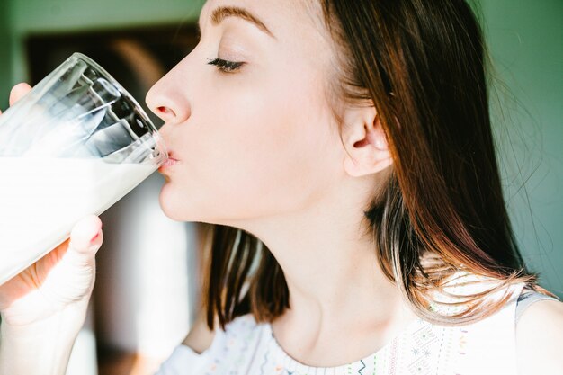 Ragazza che beve latte da un vetro