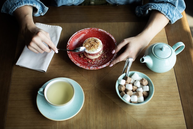 Ragazza che beve tè con un delizioso dessert