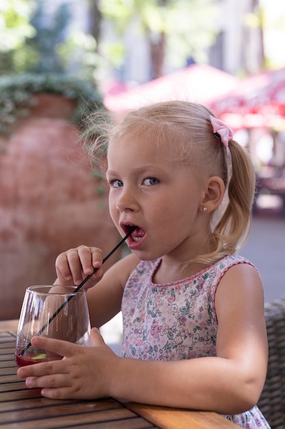 Ragazza che beve un drink sulla terrazza estiva sotto la luce naturale. Persone reali.