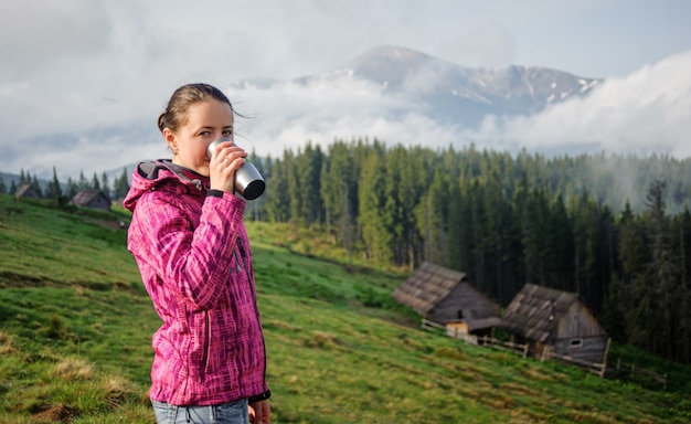 Ragazza che beve una tazza di caffè di mattina nelle montagne