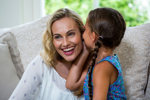 Ragazza che bisbiglia in orecchio sorridente della madre