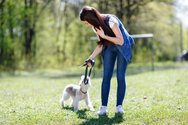 Ragazza che cammina con il cane al guinzaglio in un parco estivo