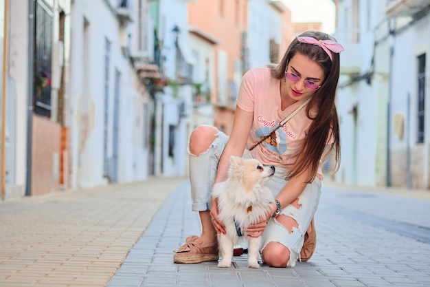 Ragazza che cammina con il suo pomeranian lanuginoso bianco.