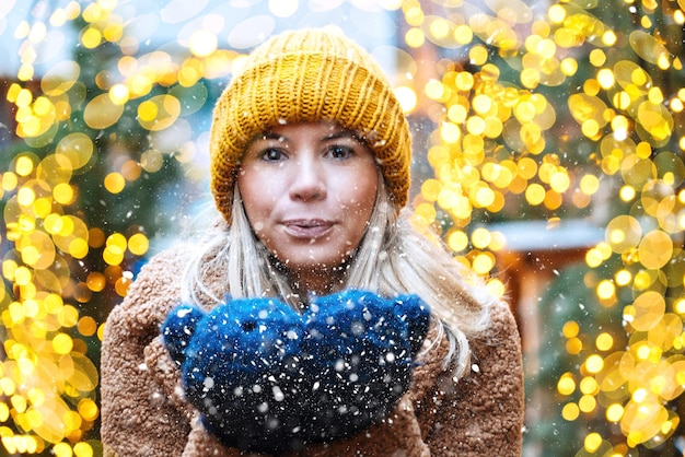 Ragazza che cammina nel mercato tradizionale di natale decorato con luci natalizie la sera d'inverno